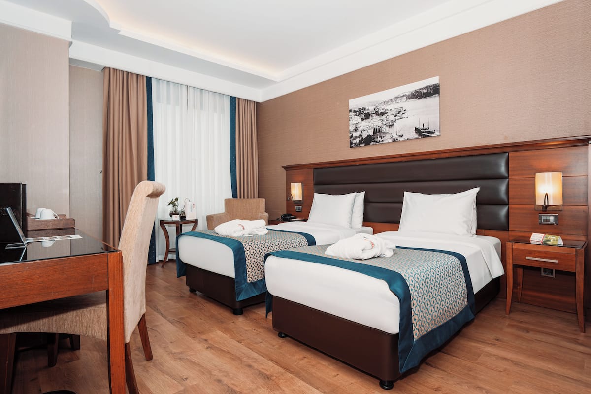 A hotel room with two beds, a desk, and a chair.