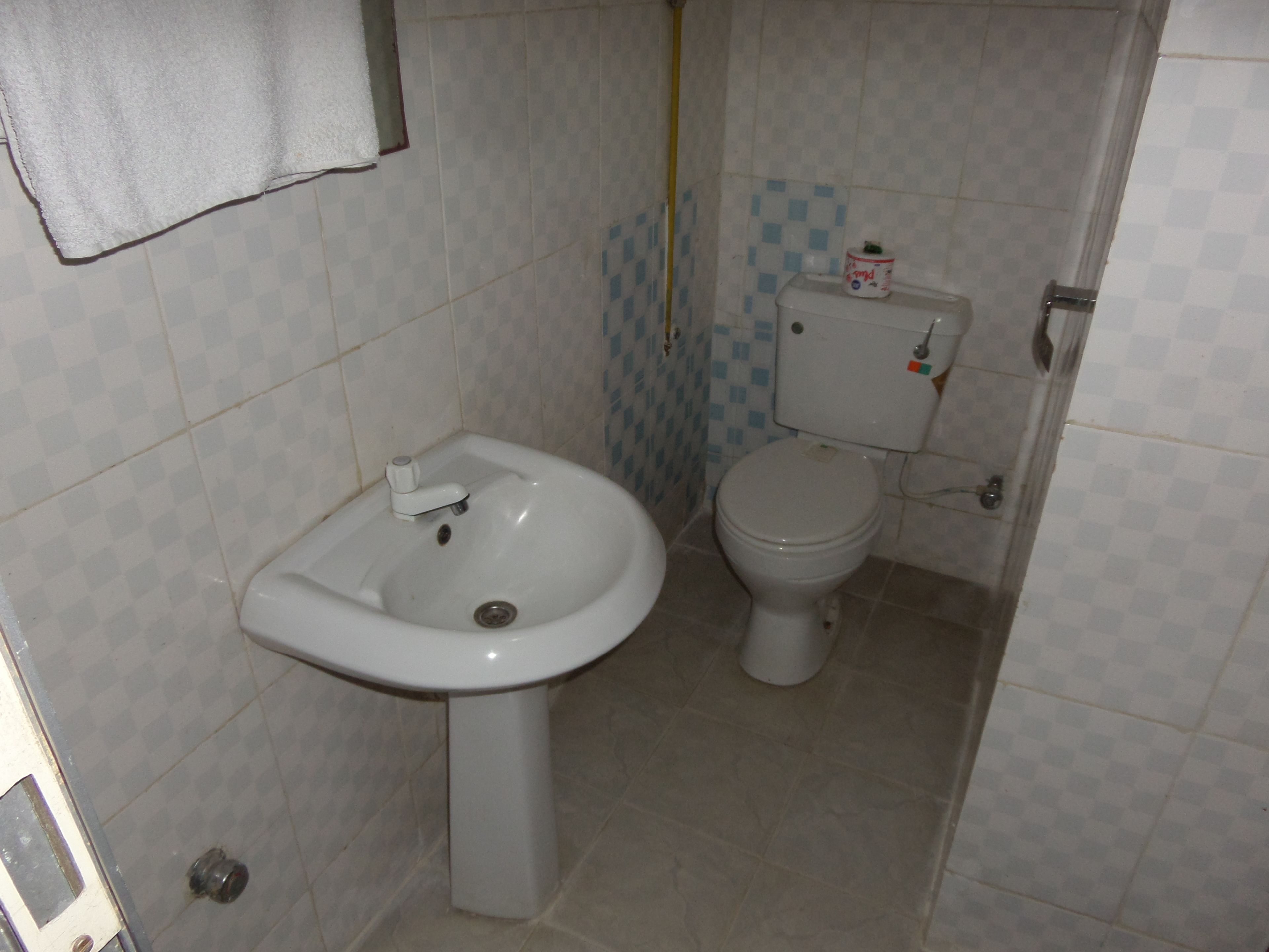 Un baño pequeño con lavamanos, inodoro y paredes con azulejos.