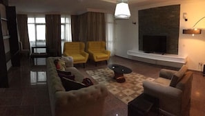 Relax in a spacious living area with a large flat-screen TV, comfortable seating, and a cozy fireplace.