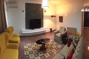 Relax in this stylish living room with a flat-screen TV, comfortable sofa, and cozy armchair.
