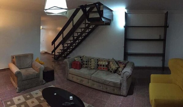 Relax in this cozy living space with a sofa set, armchairs, and ottoman.