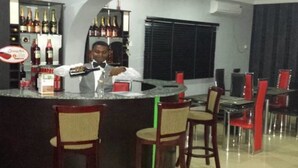 A bar area with a counter, chairs, and shelves with bottles. - L'avalon Hotel and Suites (Lekki)