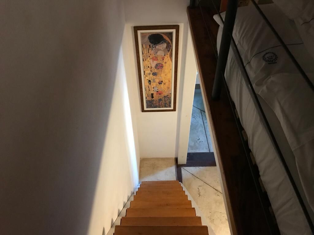 Escada que leva a um quarto com uma obra de arte emoldurada na parede.