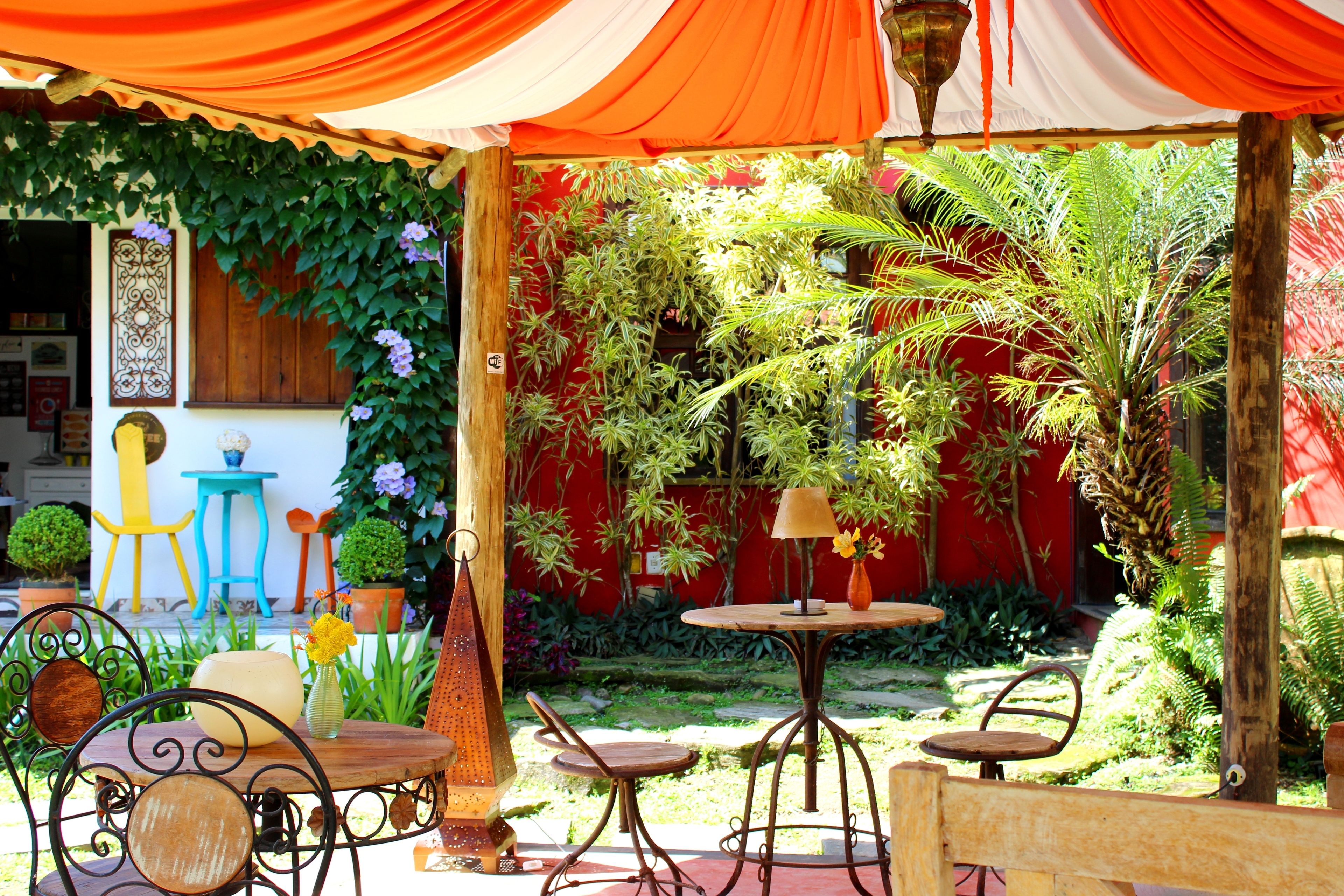 Un patio exterior con una pared roja, una mesa de madera y varias sillas.