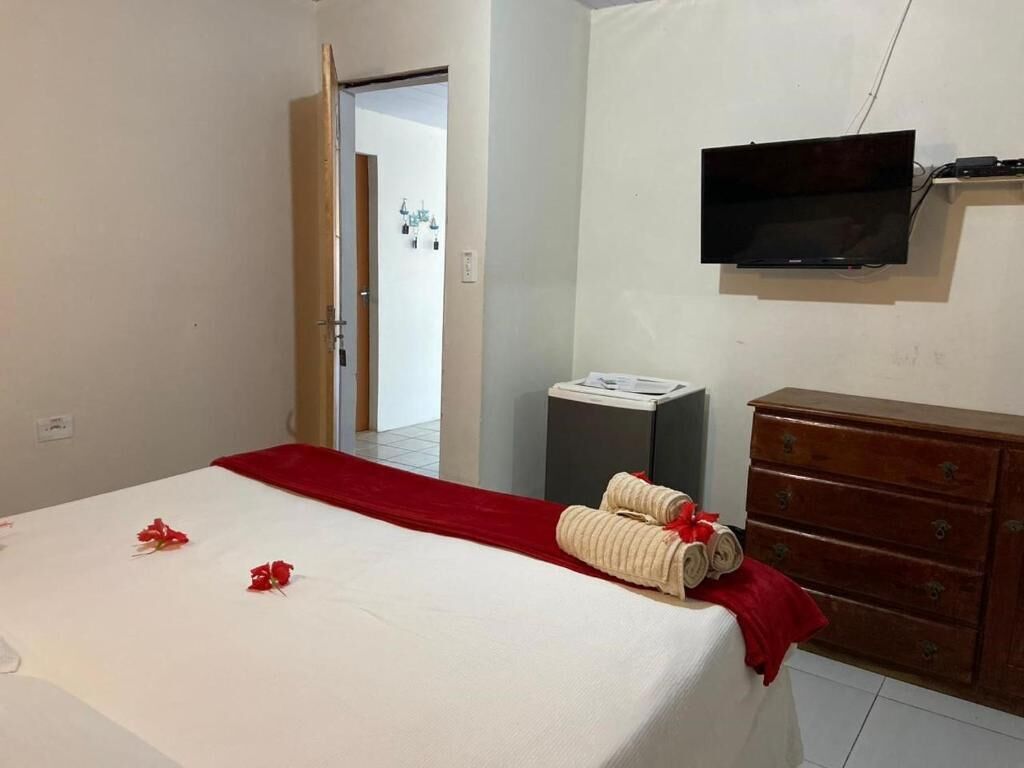 A hotel room with a bed, a television, a dresser, and a small table with a lamp.