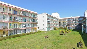 A multi-story hotel with balconies, a central courtyard with benches, and a small garden area. - Muszelka Apartments - Very close to the beach and walking paths (Sopot)