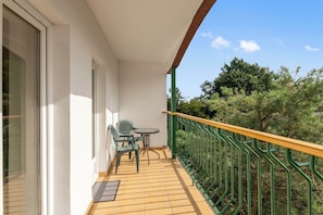 A balcony with a wooden floor, a green railing, and two chairs. - Muszelka Apartments - Very close to the beach and walking paths (Sopot)