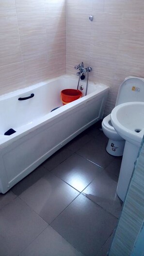 A bathroom with a bathtub, a toilet, and a sink. - Mayoral Hotel & Suite (Lagos)