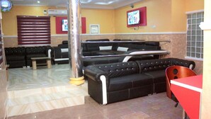 Un restaurante con sofás de cuero negro, una mesa roja y un pilar grande.