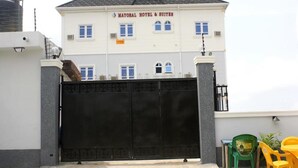 Un hotel con entrada protegida por un portón, múltiples ventanas y un cartel que dice "MAYORAL HOTEL & SUITES".
