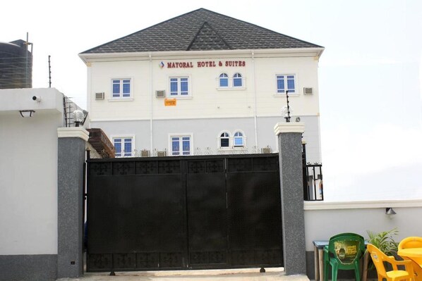 A hotel with a gated entrance, multiple windows, and a sign reading "MAYORAL HOTEL & SUITES". - Mayoral Hotel & Suite (Lagos)