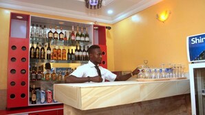 Zona de bar con mostrador, estantes con botellas de licores y un cartel que dice "Shin".