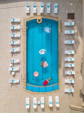 Vista aérea de una piscina con sillones de descanso alrededor.