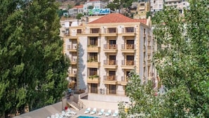 Un hôtel doté d’une piscine, de plusieurs balcons et offrant une vue sur un paysage vallonné.