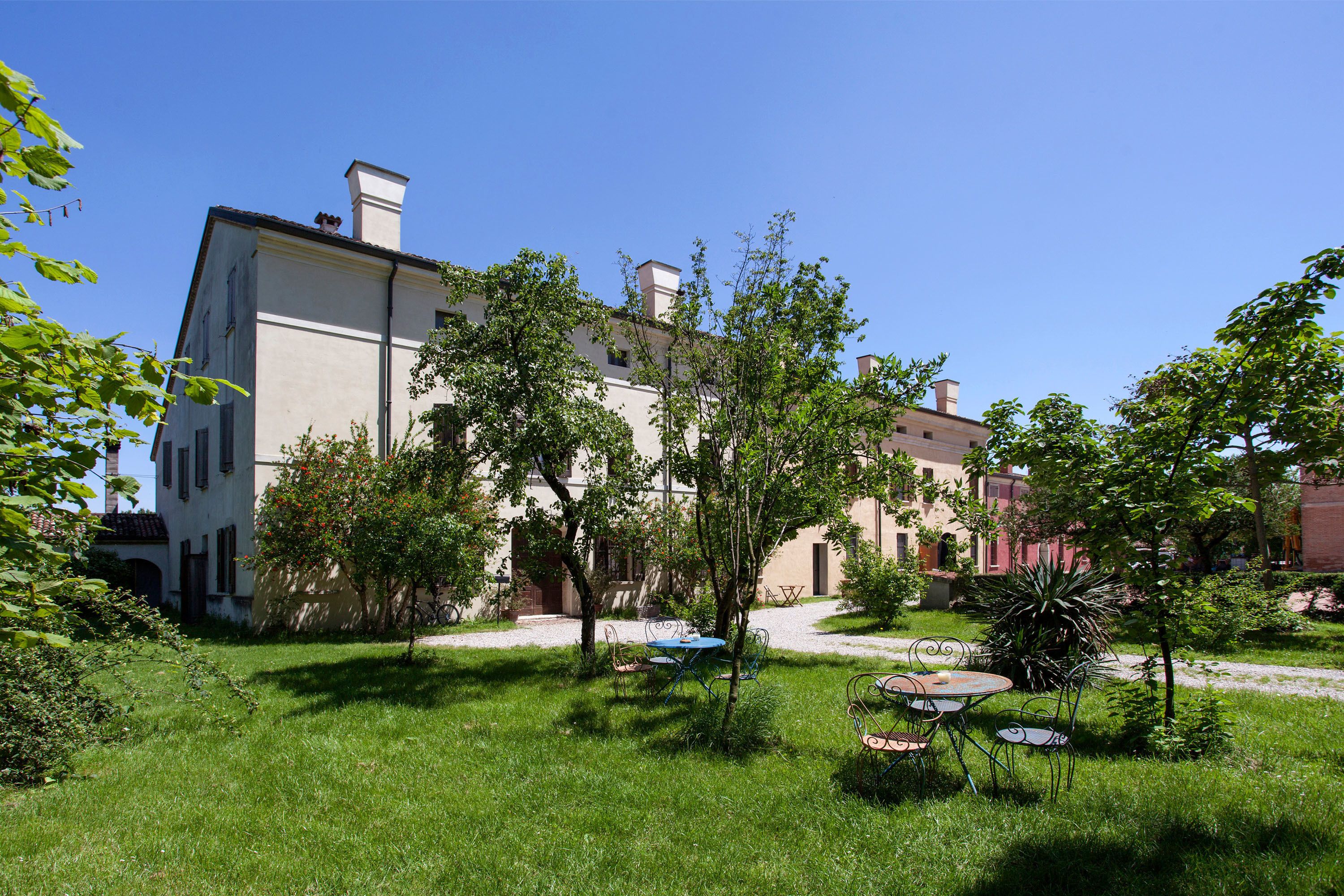 A courtyard with a building, trees, and outdoor furniture.