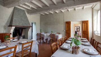 Un comedor con una mesa larga dispuesta para una comida, sillas de madera y una chimenea grande.