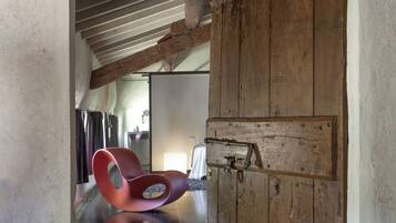 A rustic interior with exposed wooden beams, a large wooden door, and a red chair.