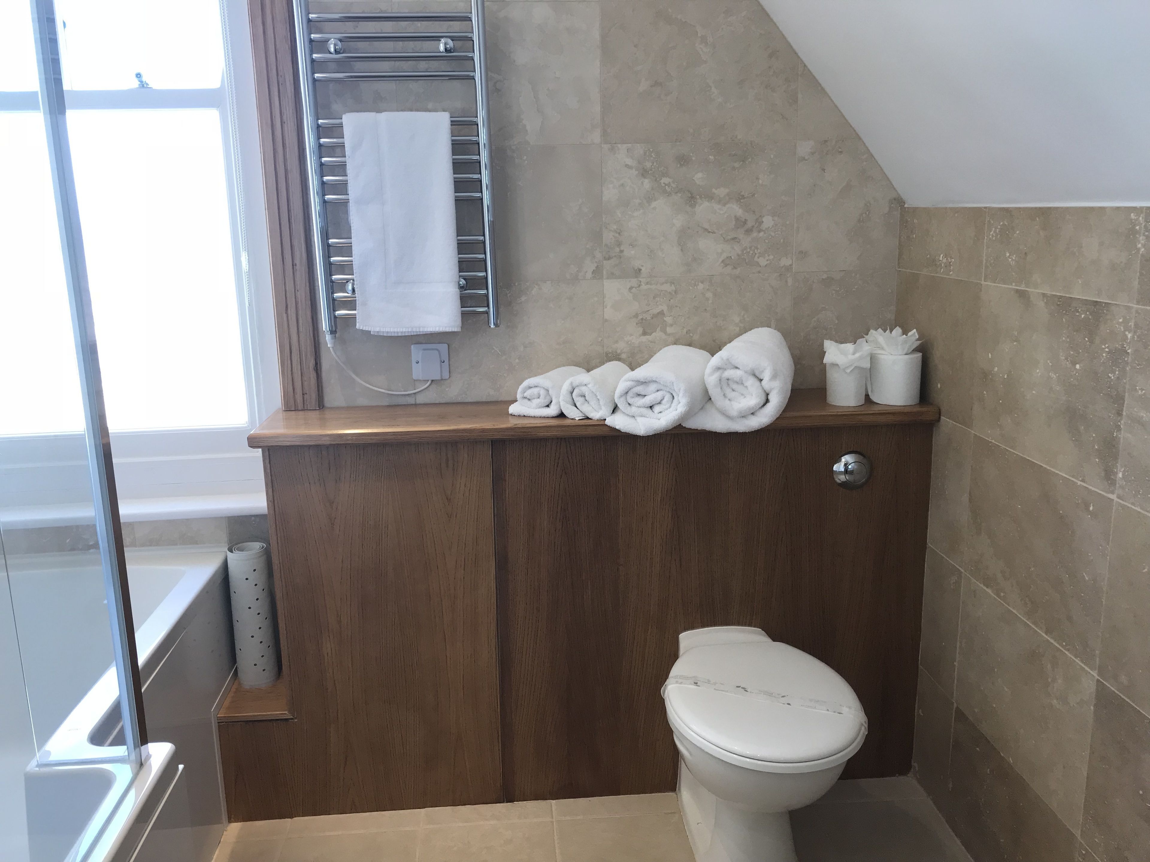 A bathroom with a wooden vanity, a towel rack with folded towels, and a toilet.