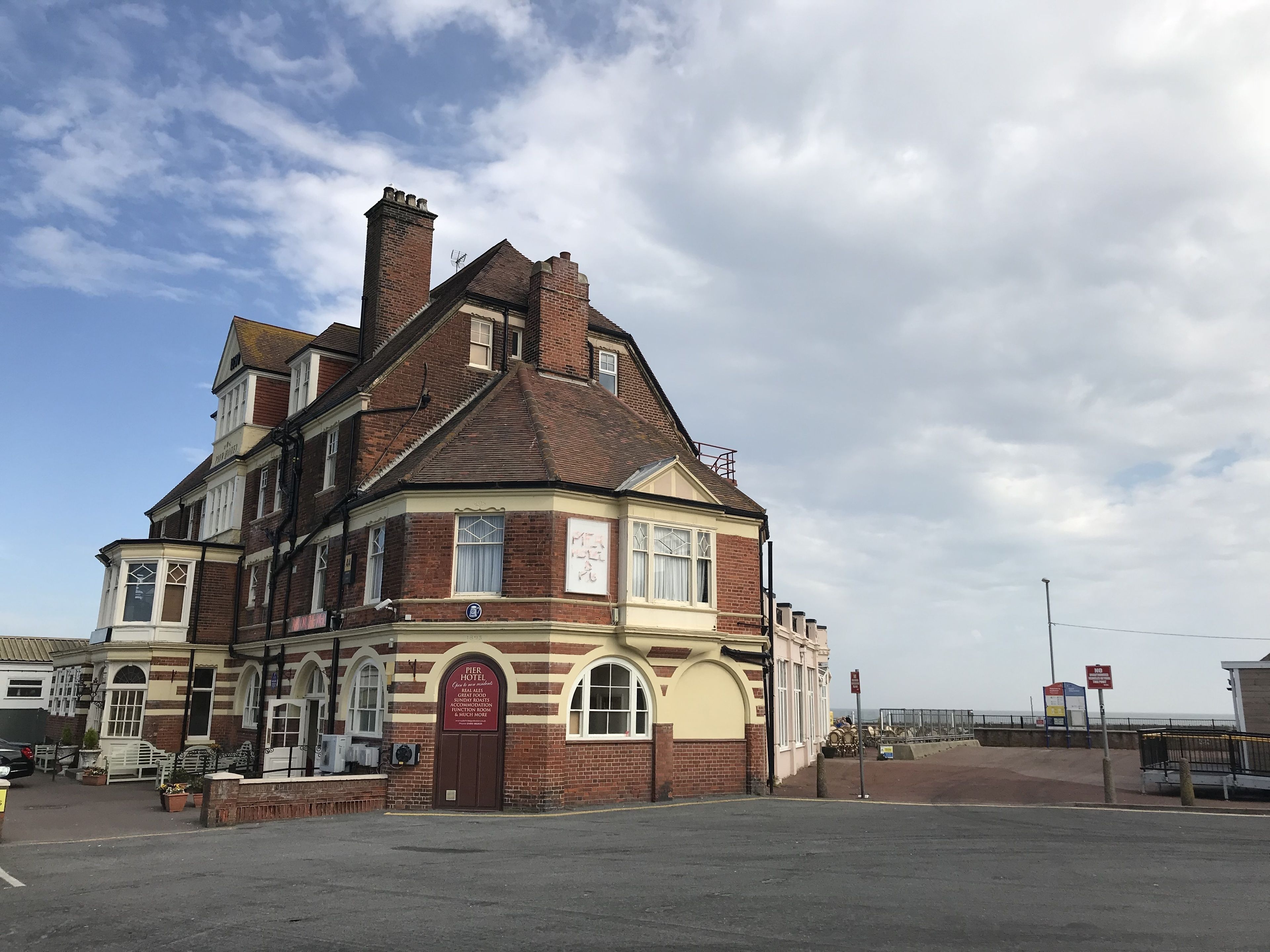 A historic hotel with a corner building, a prominent entrance, and a view of the sea.