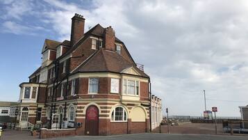 A historic hotel with a corner building, a prominent entrance, and a view of the sea.