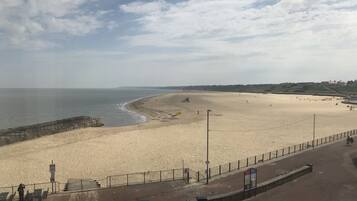A beach with a promenade, a lifeguard tower, and a safety barrier.