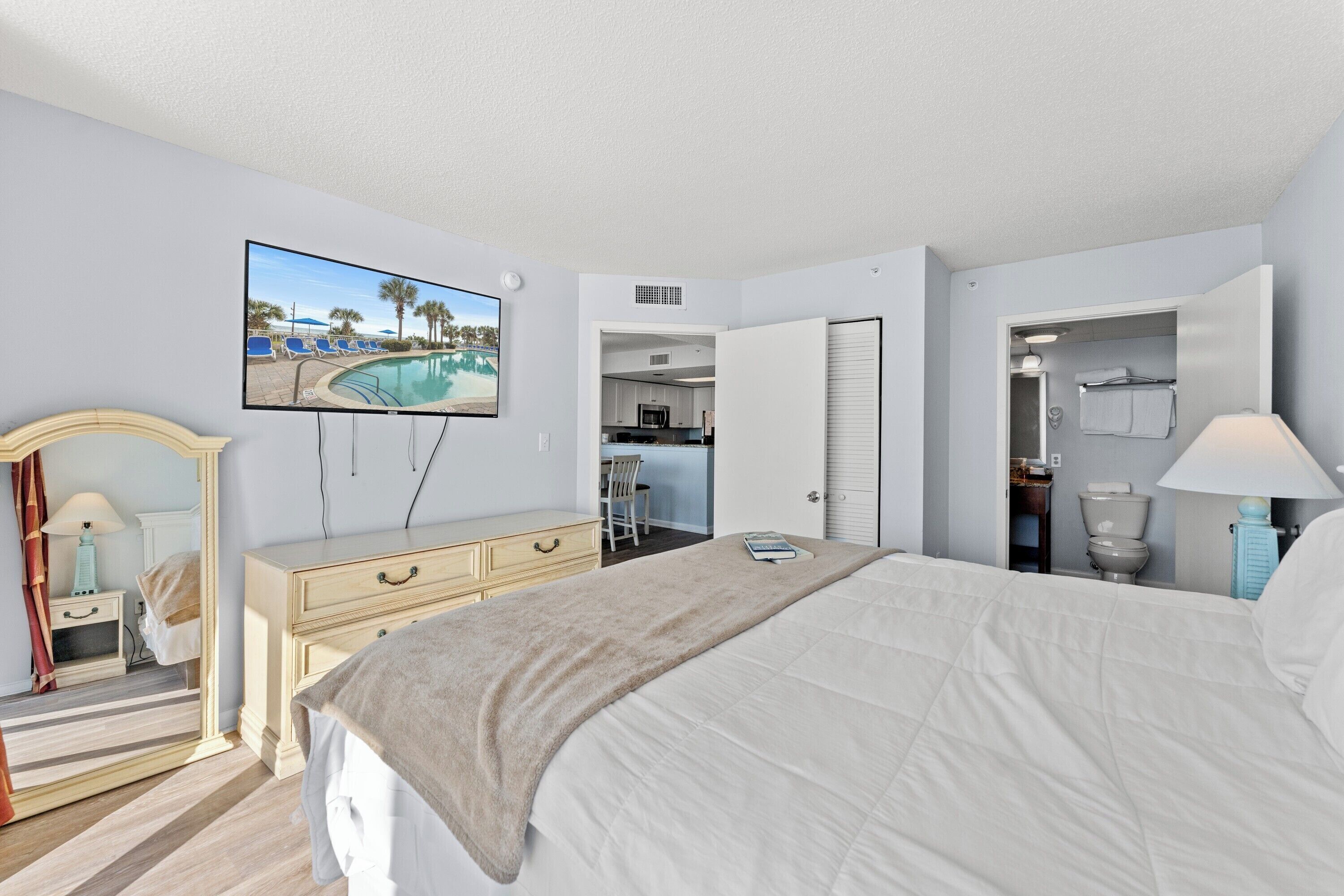 Une chambre d’hôtel comprenant un lit, un téléviseur donnant sur la piscine, une kitchenette et une salle de bain.