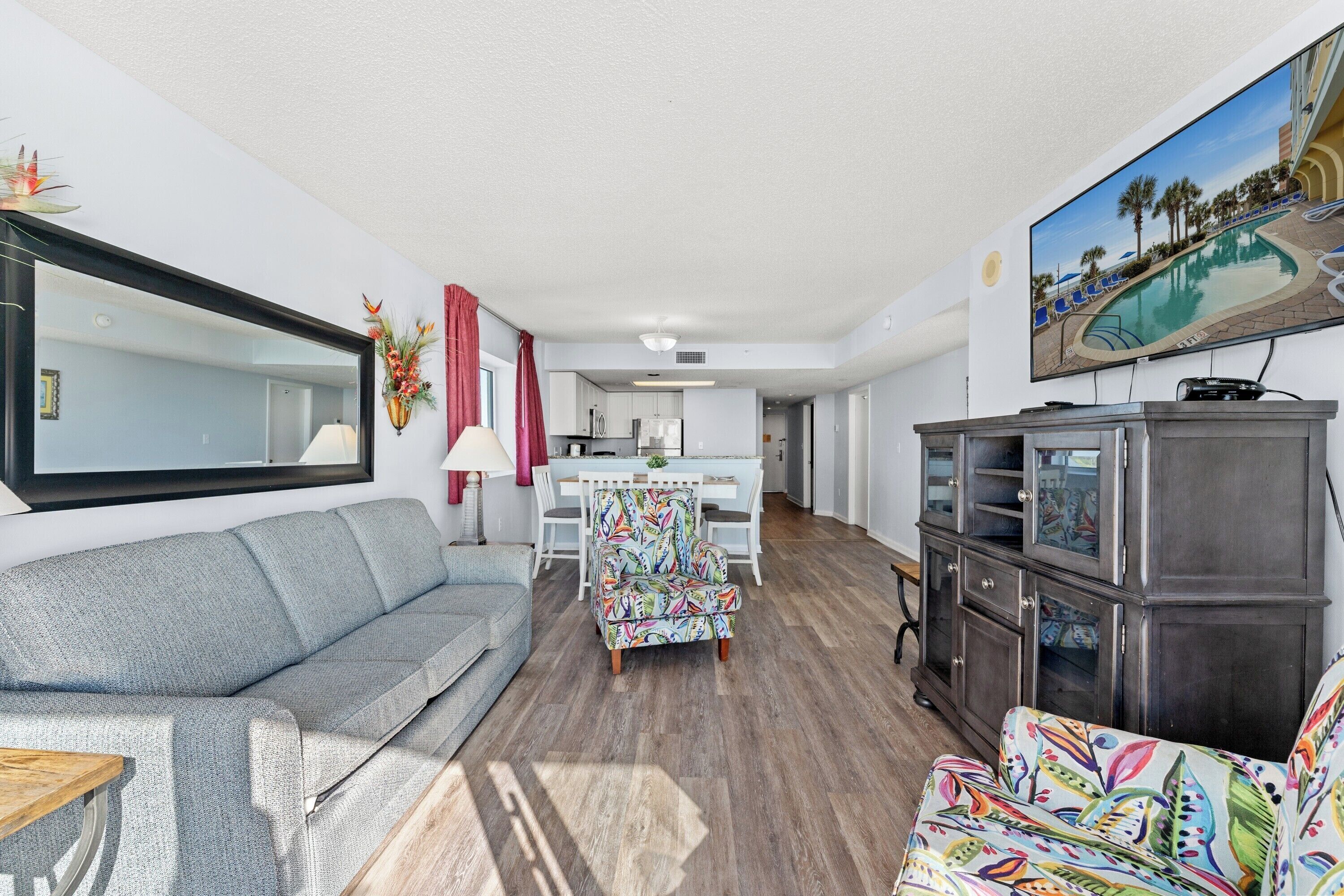 A living room with a sofa, a colorful armchair, a TV, and a cabinet.