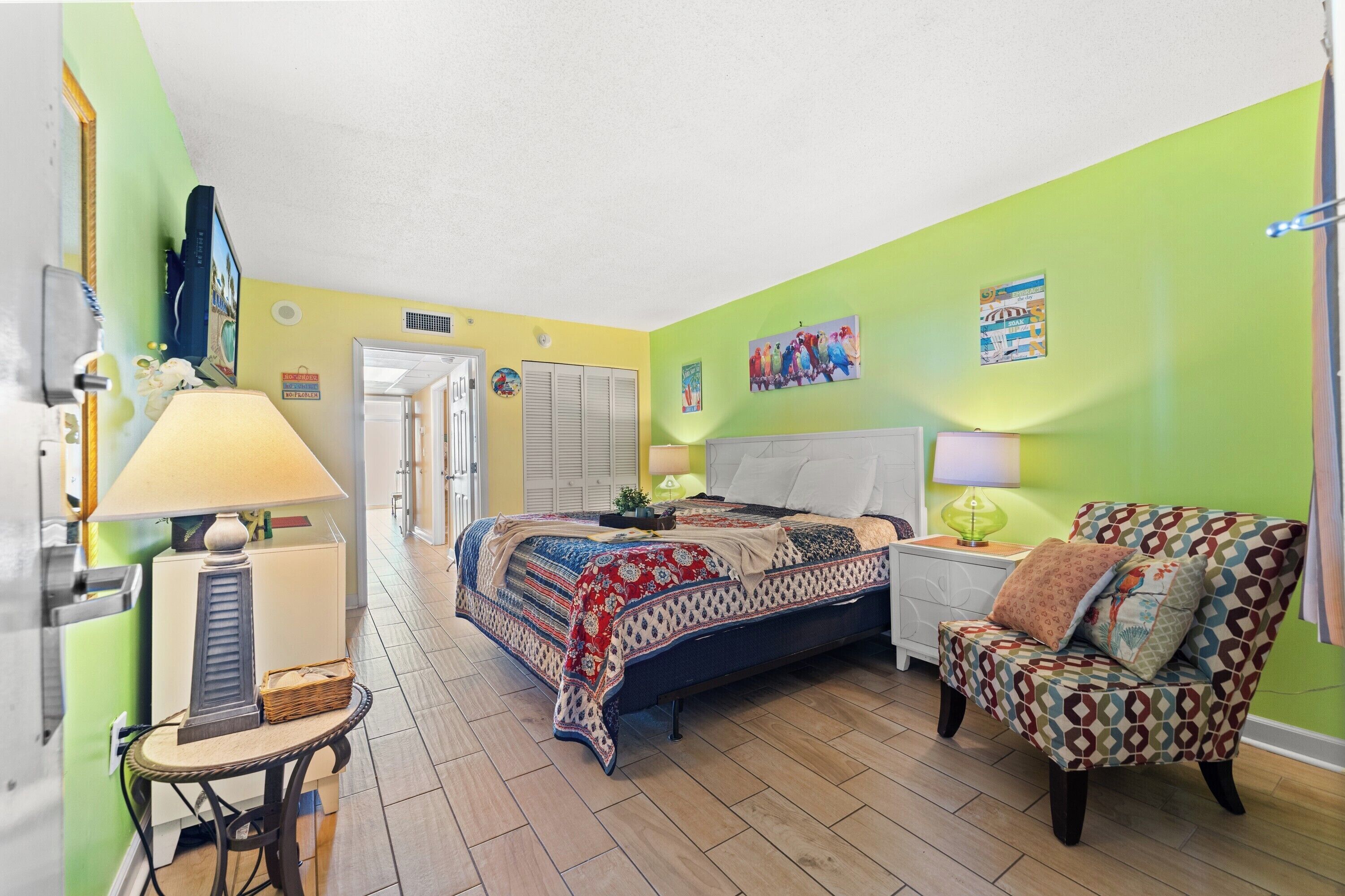 A bedroom with a bed, a chair, a lamp, and a small table.