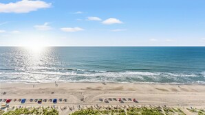 A beach with a clear sky, ocean waves, and beachgoers. - Camelot by the Sea by Elliott Beach Rentals (Myrtle Beach)