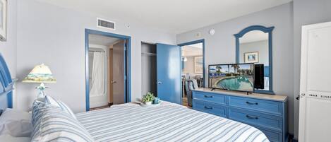A bedroom with a bed, a dresser, a mirror, and a door leading to a bathroom.
