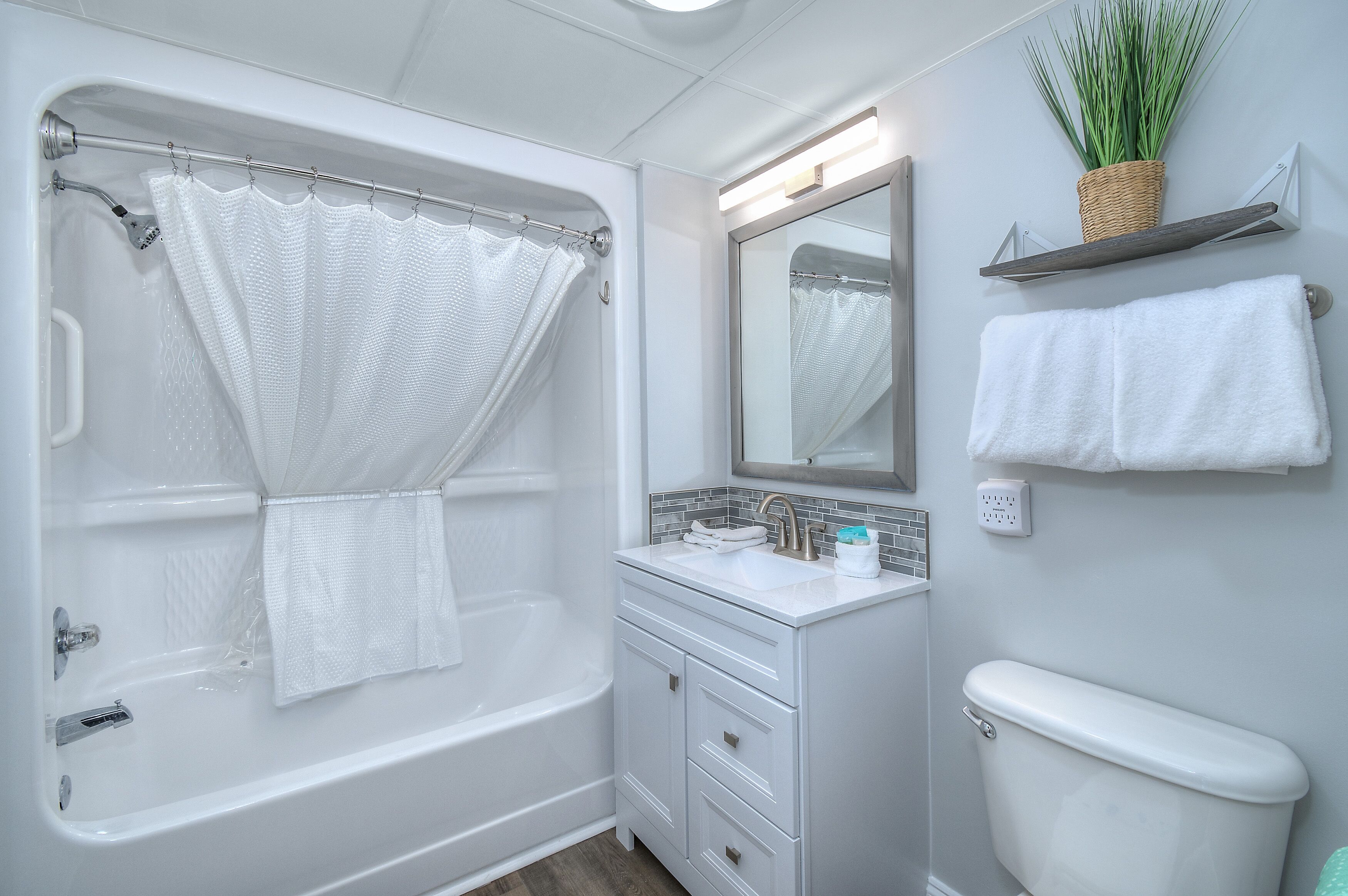 Un baño moderno con bañera, lavamanos, inodoro y espejo.