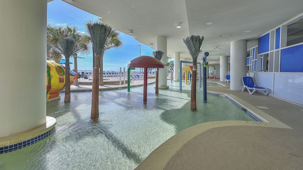 Zona de piscina interior amb tobogans, palmeres i gandules.