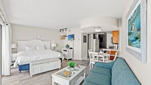A modern hotel room with a large bed, a sofa, a dining area, and a kitchen. - Units at St. Clements at Caravelle by Elliott Beach Rentals (Myrtle Beach)