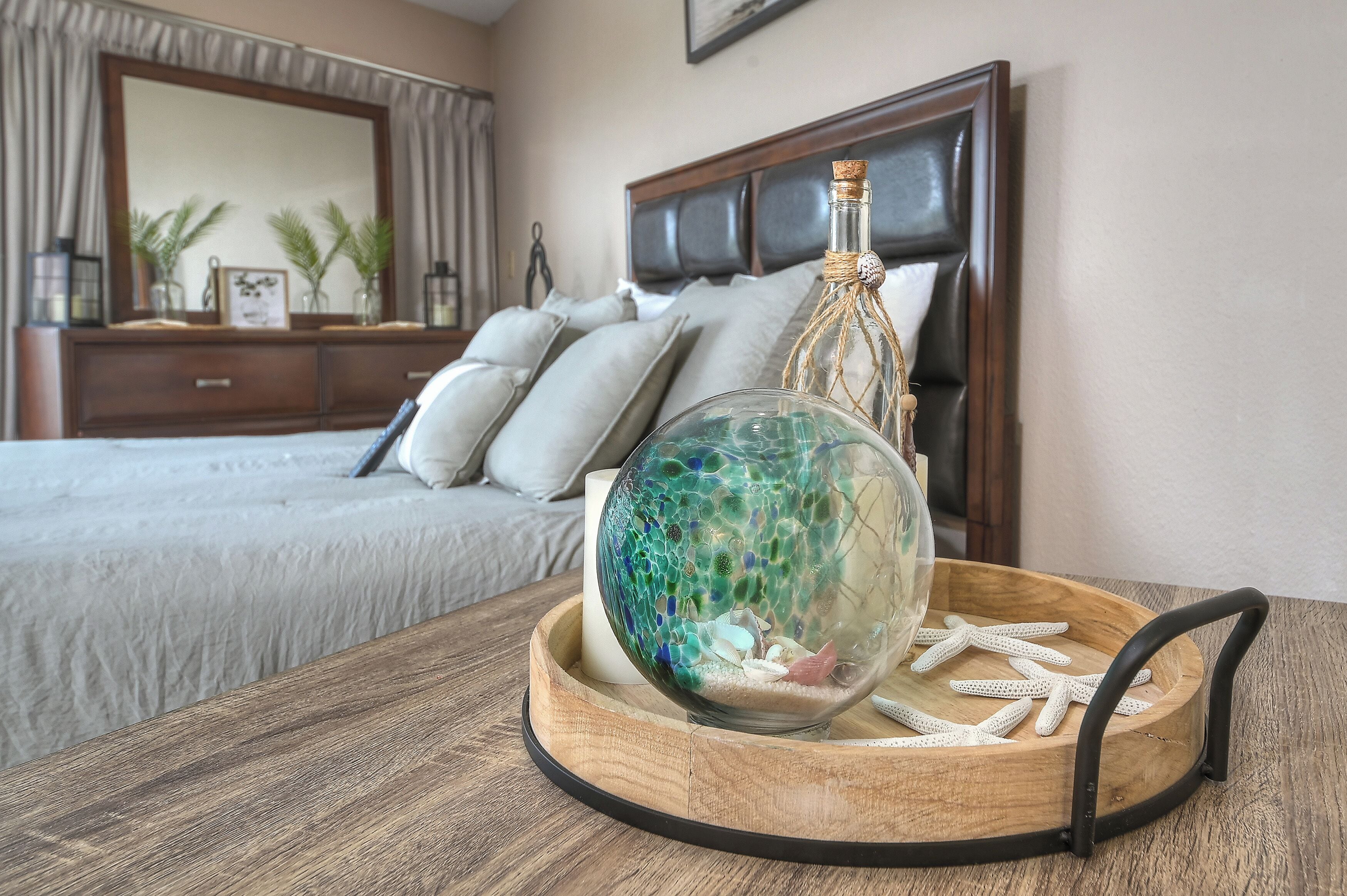 A bedroom with a bed, a dresser, a nightstand, and a decorative glass bowl on a tray with starfish.