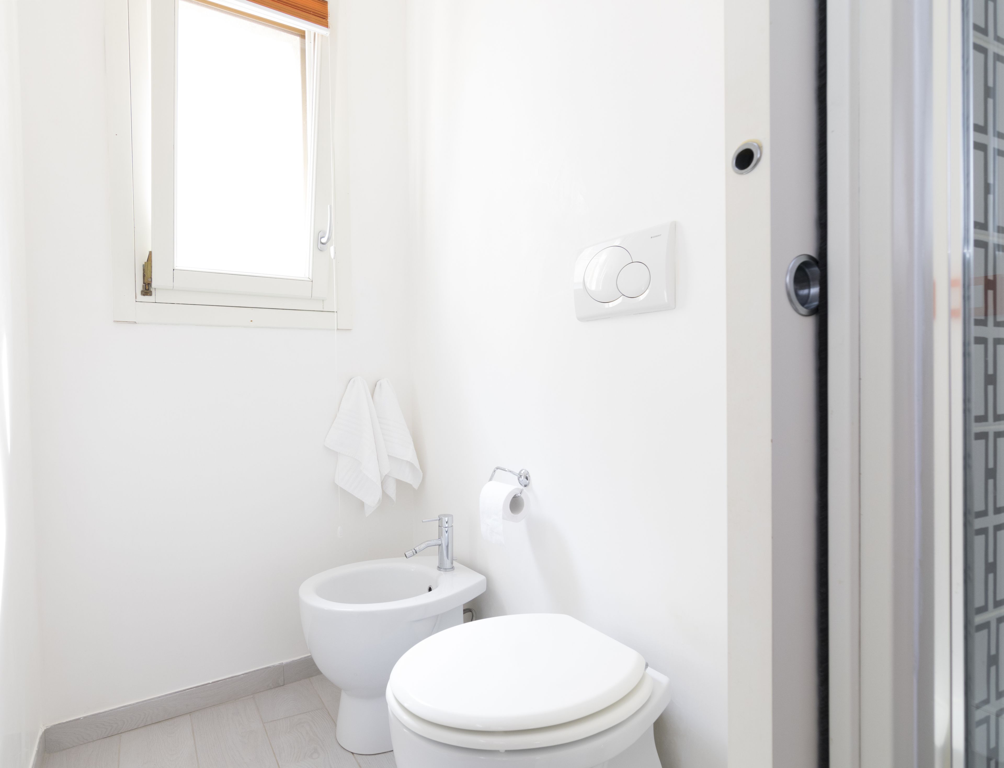 Un bany petit i net amb vàter, bidet i una finestra sobre el vàter.