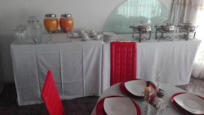 A buffet setup with clear glass containers, white plates, and red napkins. - Joezebel Guest House (Moses Kotane)