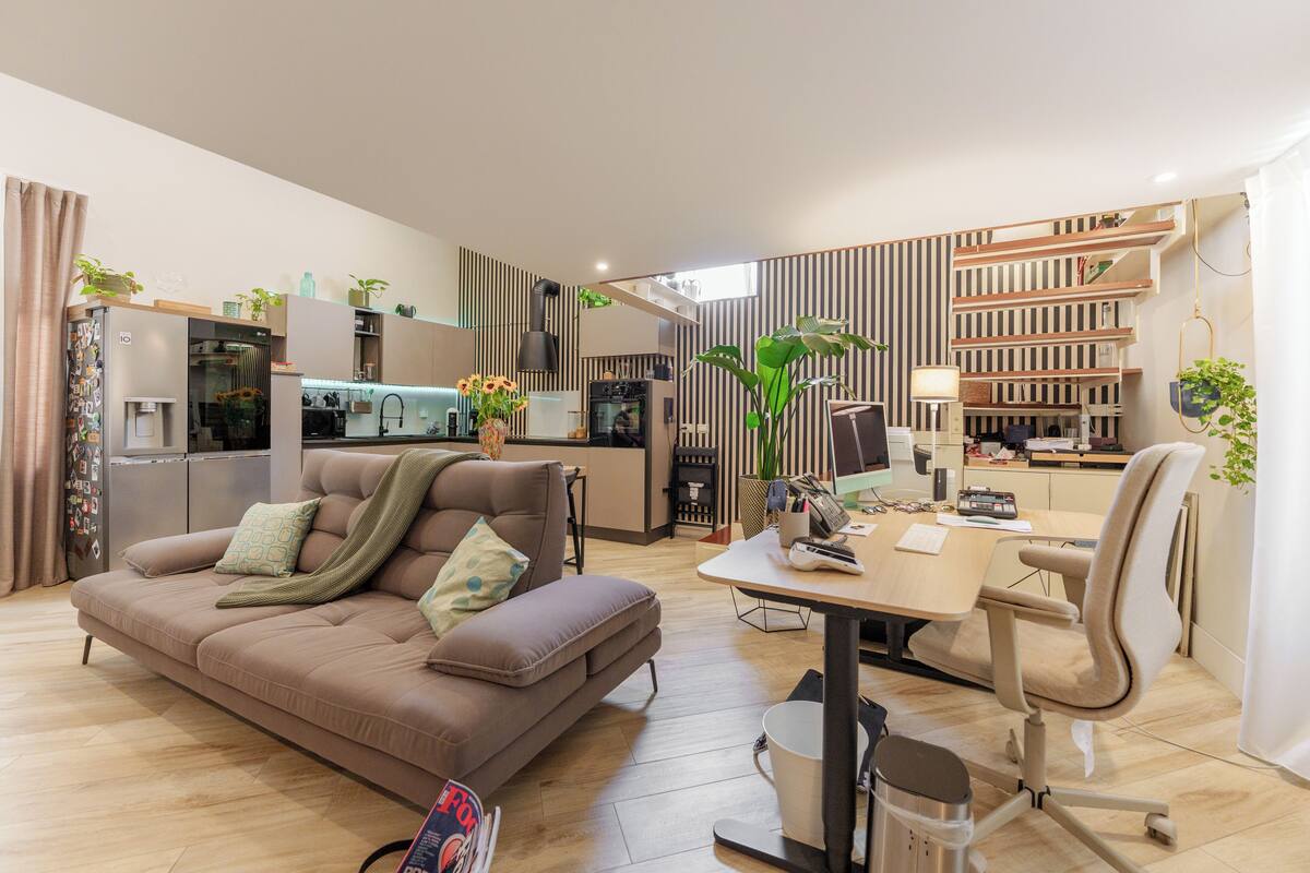 Ein modernes Wohnzimmer mit einer Couch, einem Esstisch und einer Küche im Hintergrund.