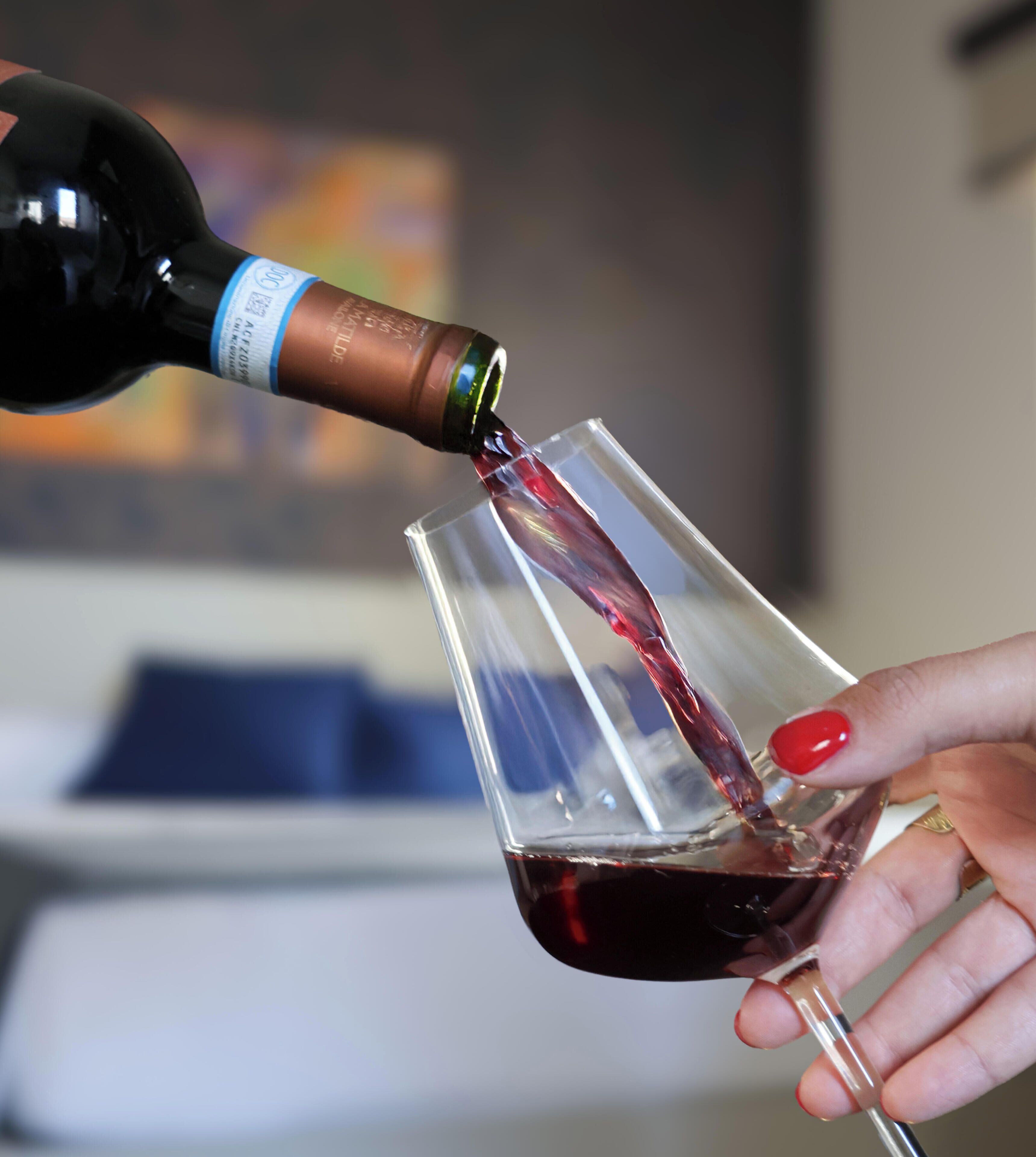 Una mano versa vino rosso da una bottiglia in un bicchiere.