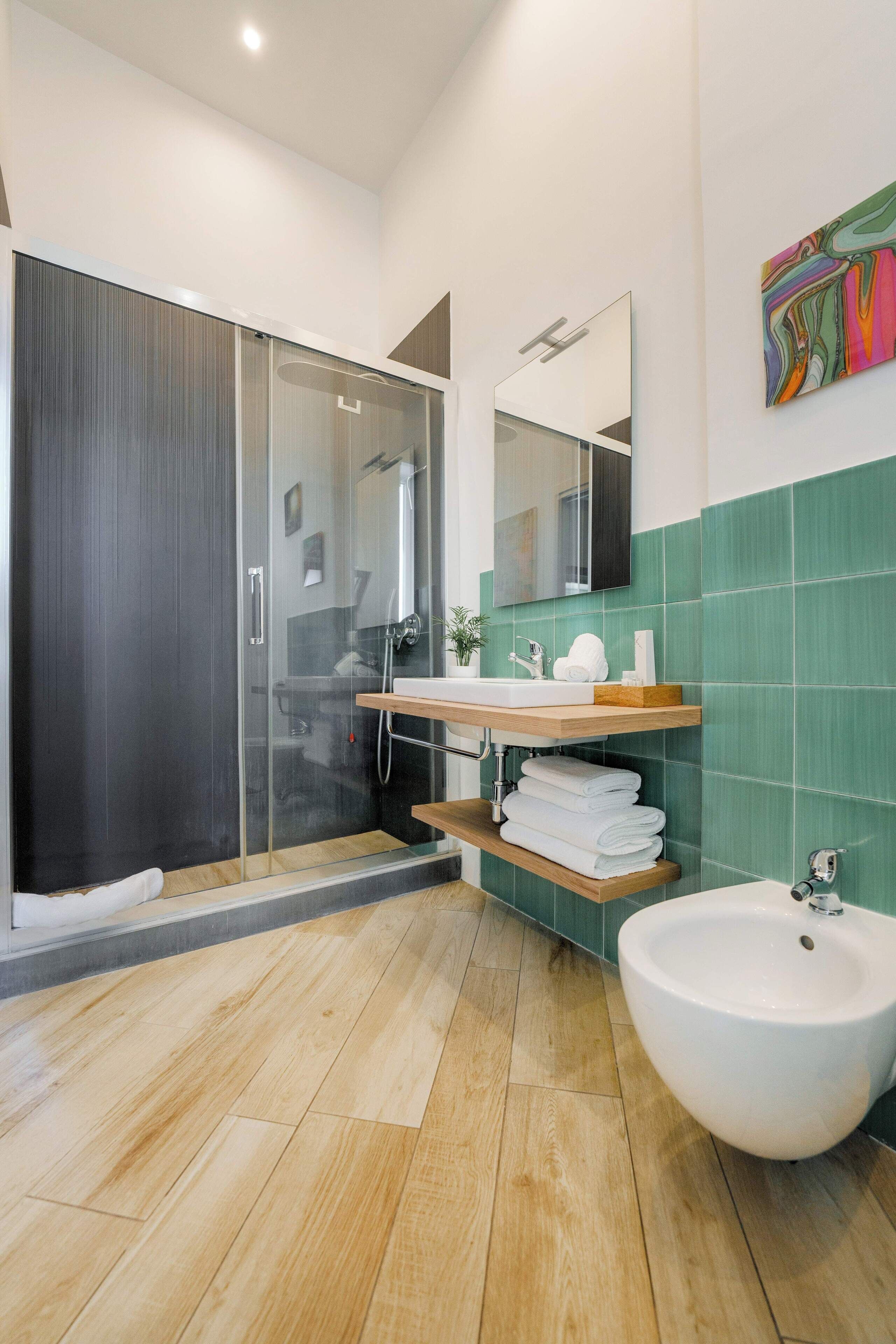A modern bathroom with a glass shower enclosure, a white sink, and a bidet.
