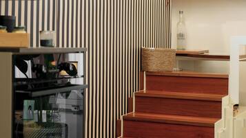 Een moderne keuken met een houten trap, een gestreepte wand en diverse keukengadgets.