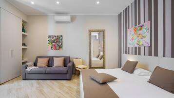 A modern bedroom with a bed, a sofa, a chair, and a large mirror.