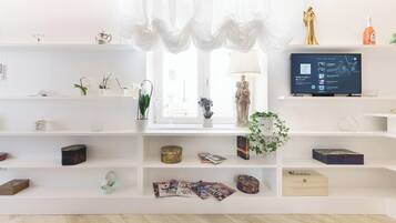Una sala de estar moderna con estanterías blancas, un televisor y varios objetos decorativos.
