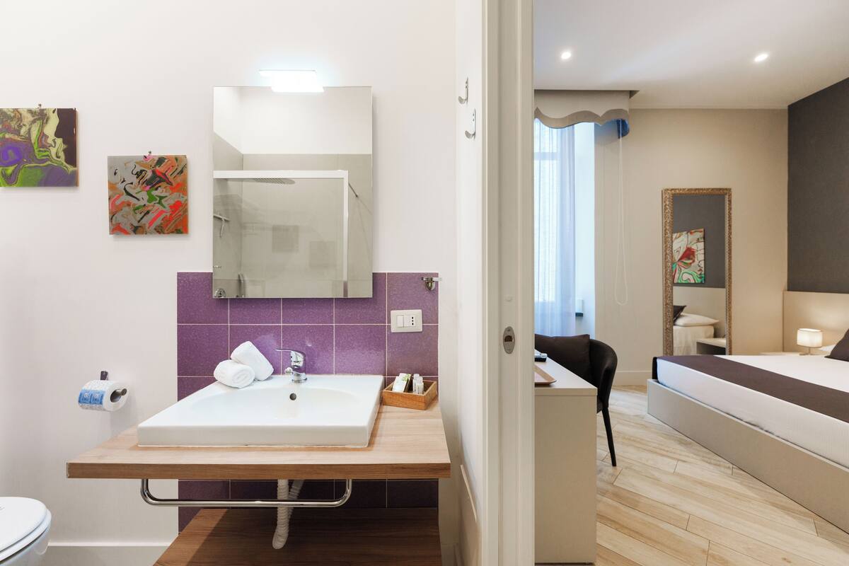 Ein modernes Badezimmer mit Waschbecken, Spiegel und violetten Fliesen.