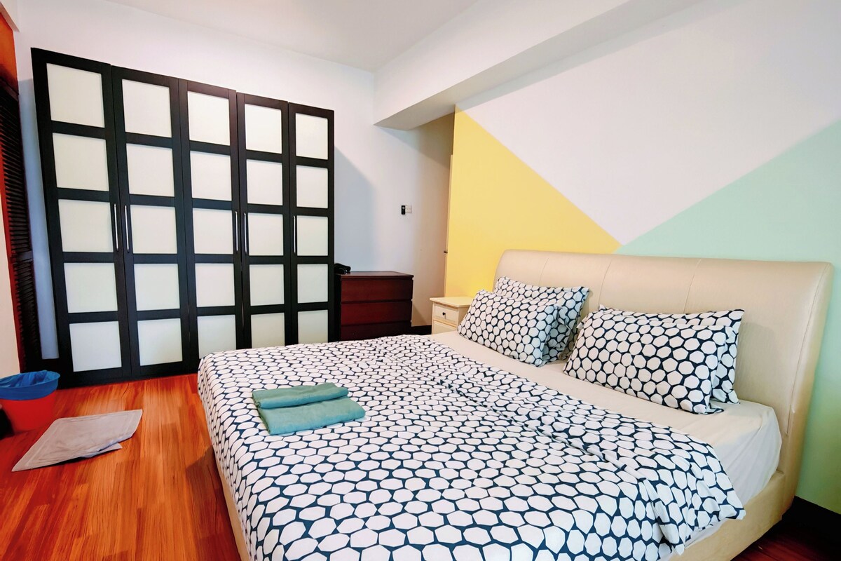 A bedroom with a bed, wooden floor, and a wardrobe with a sliding door.