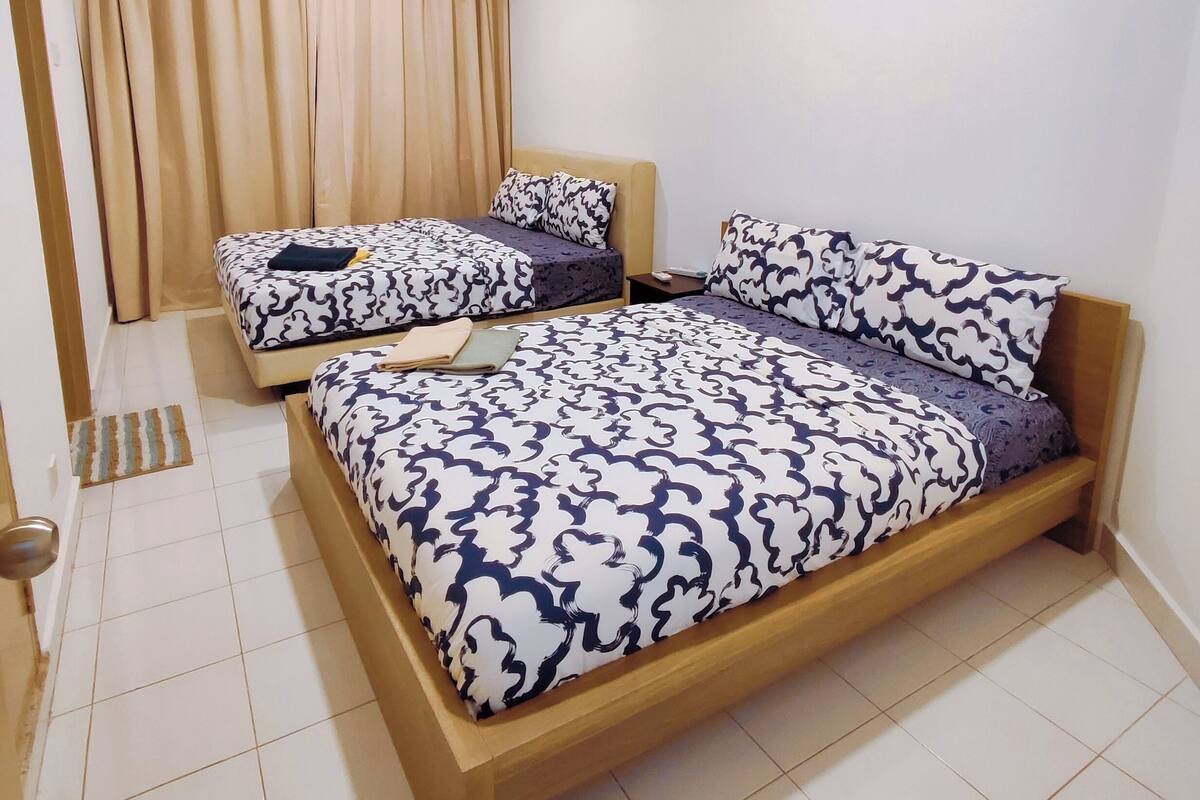 A bedroom with two beds, a window with curtains, and a tiled floor.