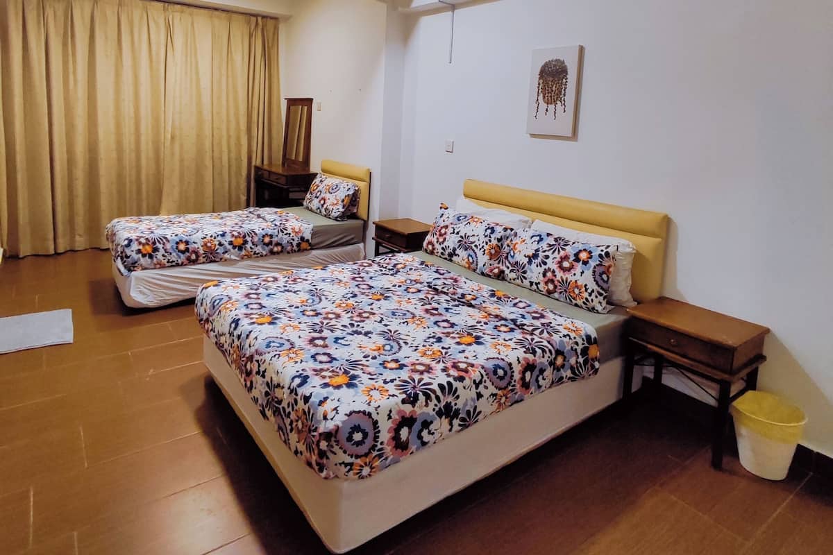 A hotel room with two beds, a ceiling fan, a wooden floor, and a window with curtains.