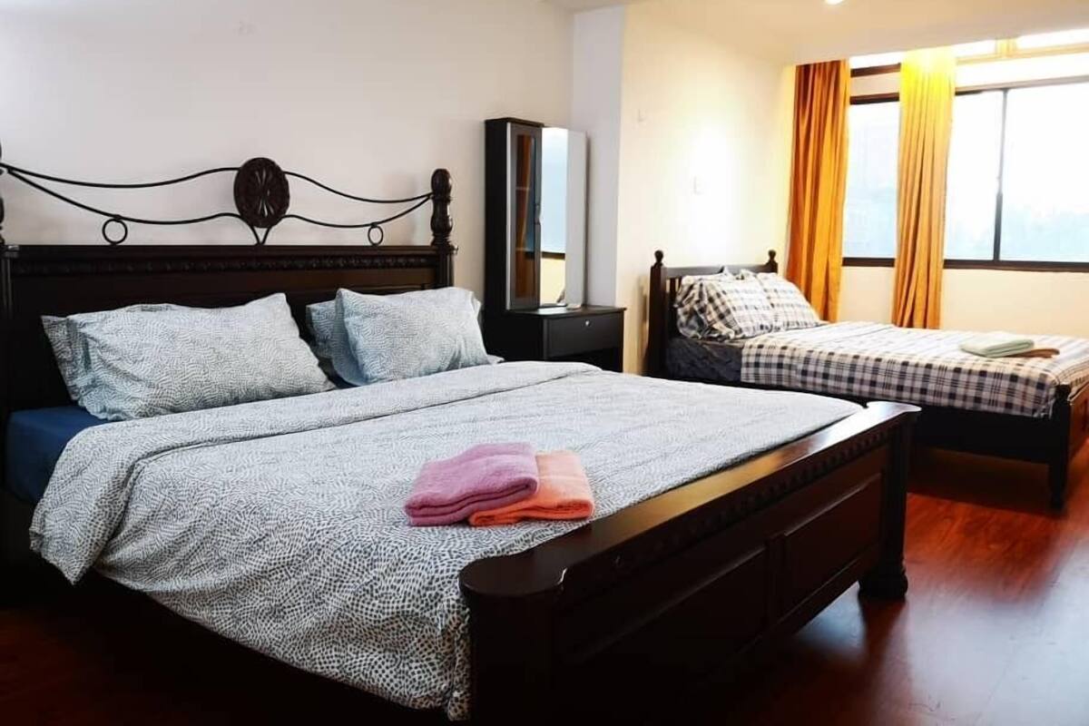 A hotel room with two beds, a wardrobe, a mirror, and a window with curtains.