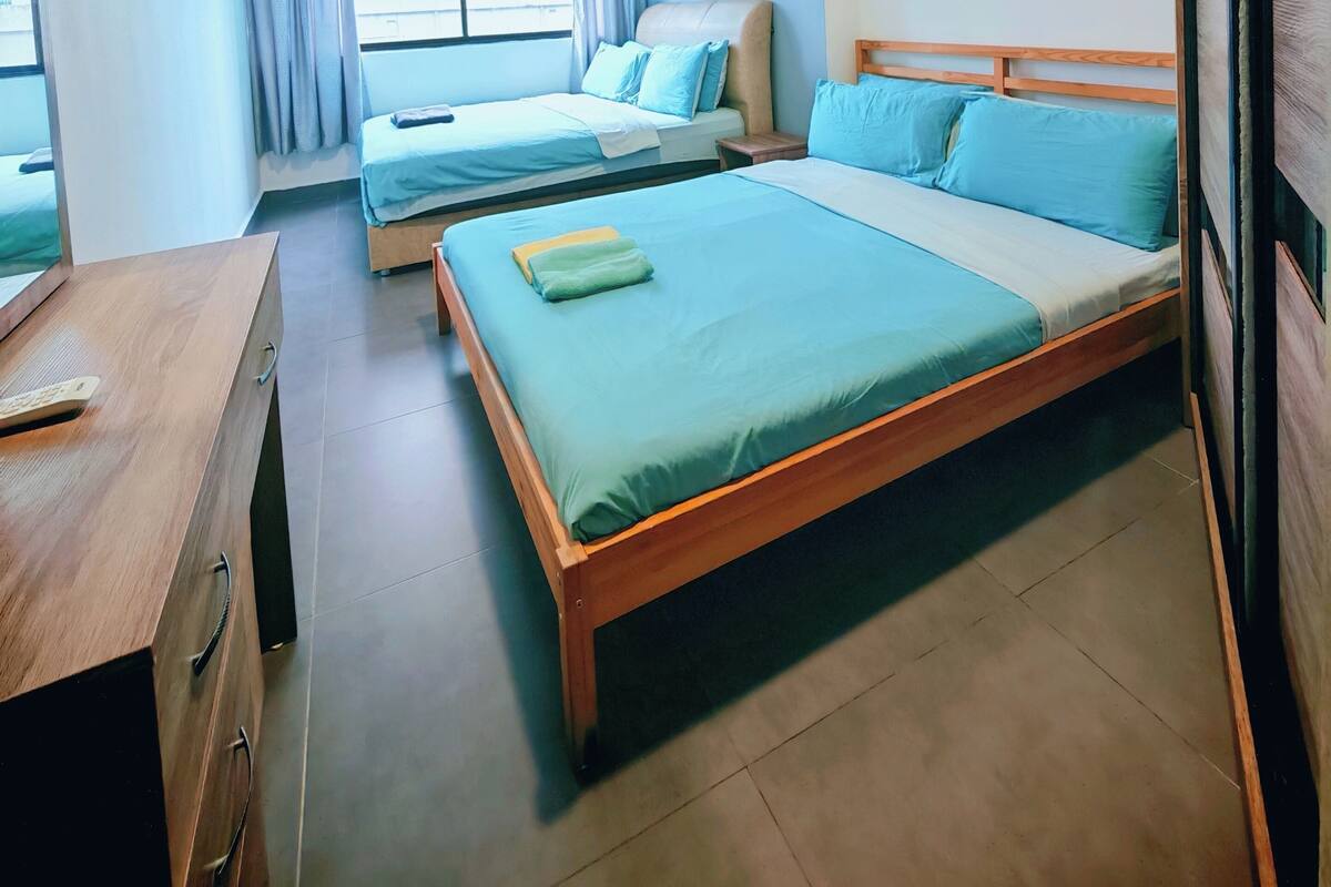 A hotel room with two beds, a wooden desk, and a window with curtains.