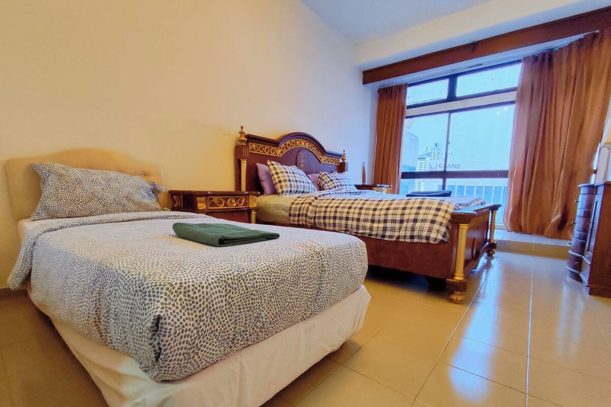 A hotel room with two beds, a balcony, and a view of the city.