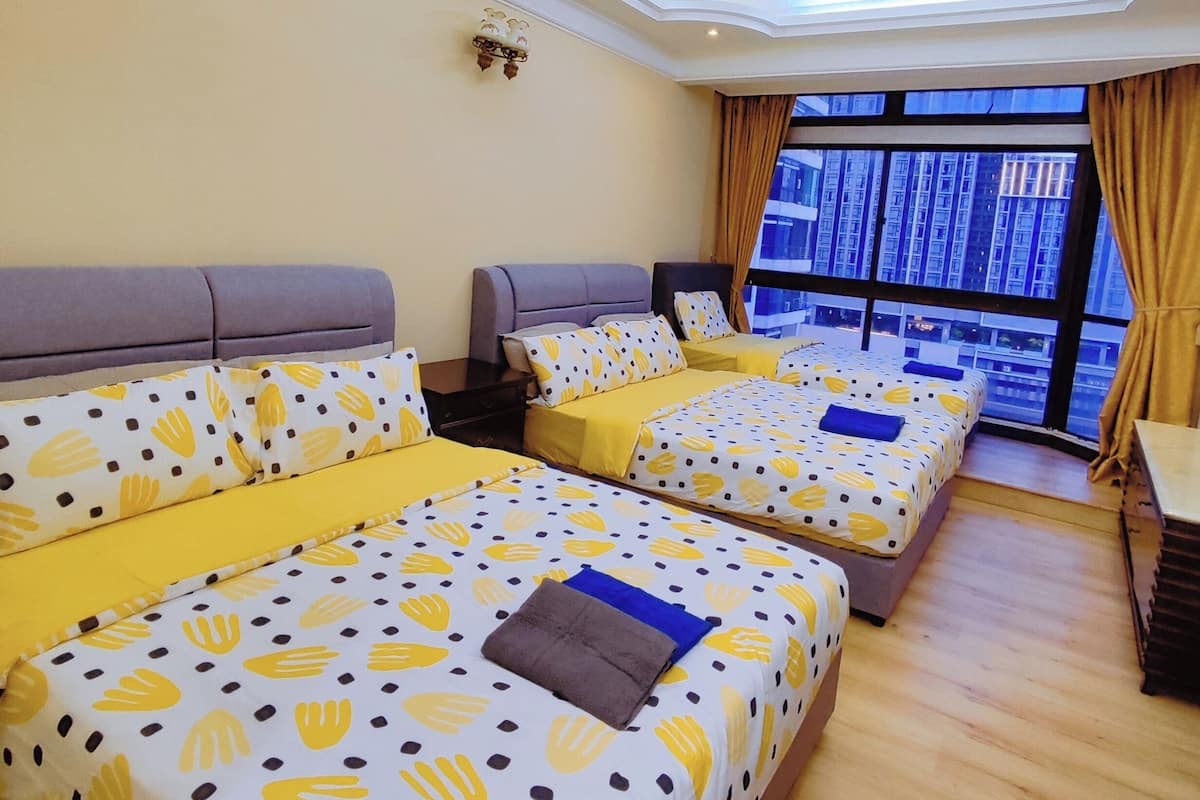 A hotel room with three beds, a ceiling fan, and a large window with a view of buildings.